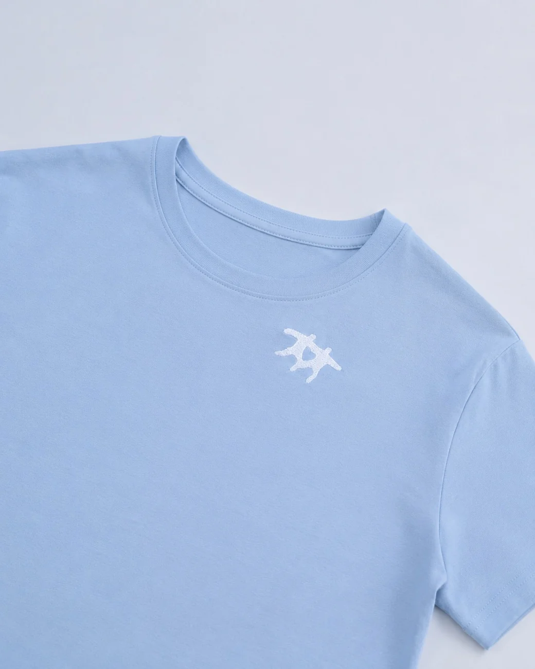 Голубая футболка с небольшой белой вышивкой у горловины